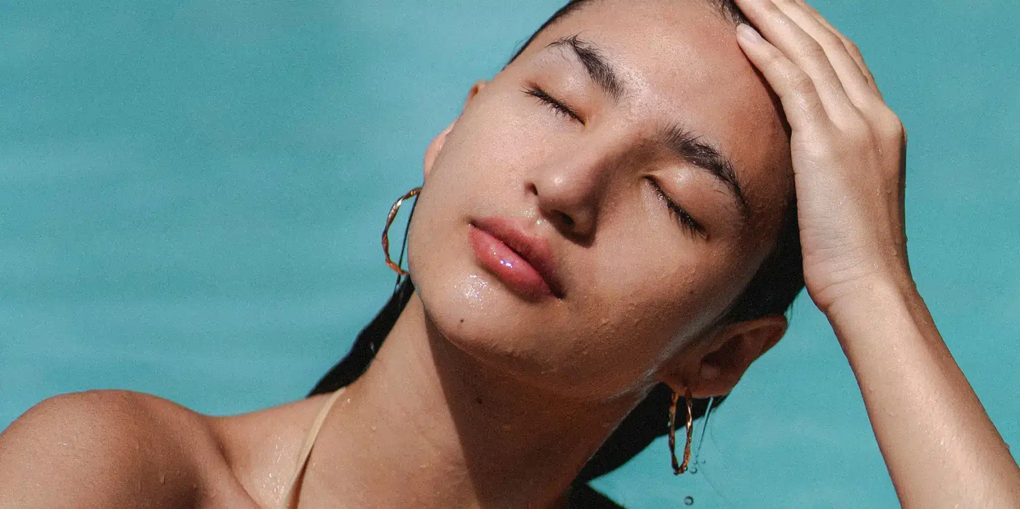 Woman relaxing in a pool with eyes closed and hand resting on her head