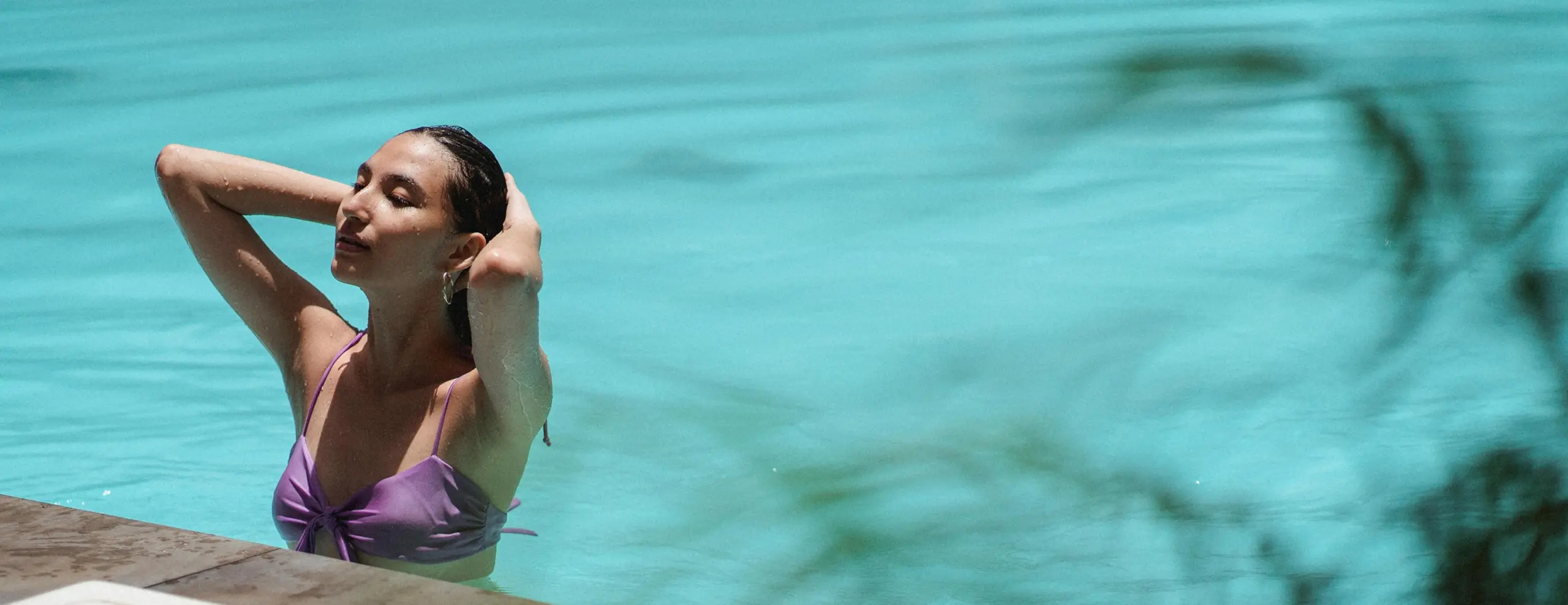 Woman in a purple swimsuit leaning back in a turquoise pool