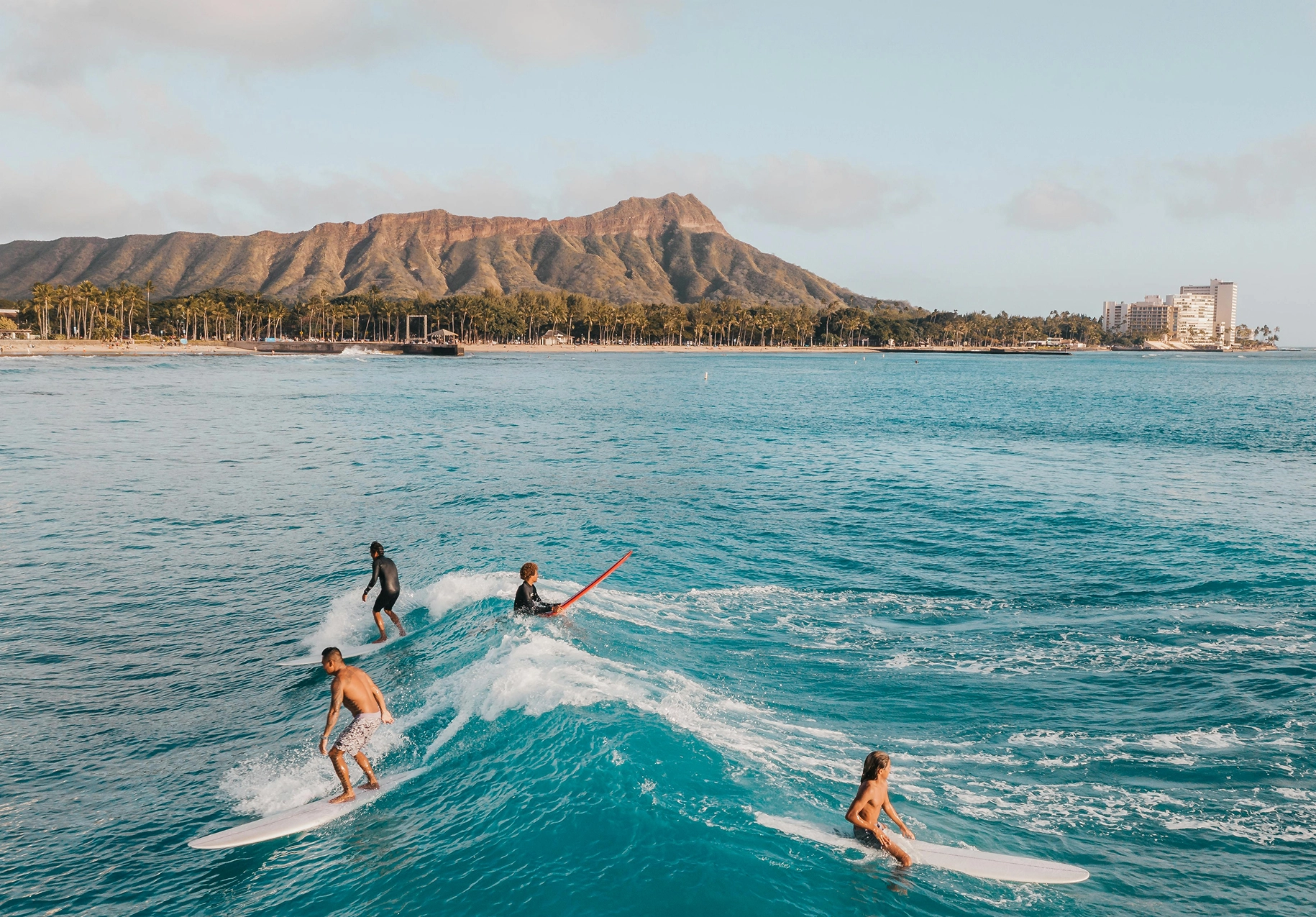 Group of surfers riding small waves with a mountain backdrop